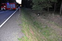 Na fotografii widać drogę w poprzek której stoi wóz strażacki. Z prawej strony zdjęcia widać przydrożny rów, w którym leży motocykl.