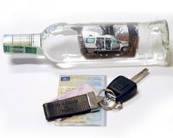 Na fotografii widać butelkę, obok której leży dowód rejestracyjny pojazdu, a na dowodzie leżą kluczyki do samochodu.