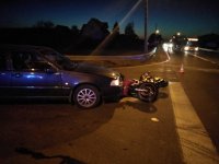 Na fotografii widać skrzyżowanie, na którym przed samochodem osobowym leży rozbity motocykl. Z prawej strony fotografii, w tle widać autobus i stojącego obok niego policjanta.