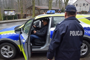 na zdjęciu komendant powiatowy przy nowym policyjnym radiowozie, w którym siedzi wójt gminy zbrosławice
