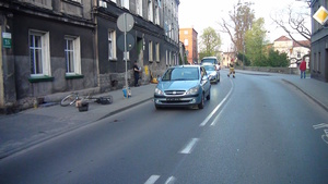 na zdjęciu na jezdni jasny pojazd, obok przewrócony rower i mężczyzna, za pojazdem radiowóz i strażak
