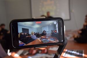 na zdjęciu w pierwszym planie ekran telefonu nagrywającego spotkanie